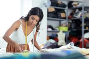 beautiful young seamstress cutting silk fabric new dress