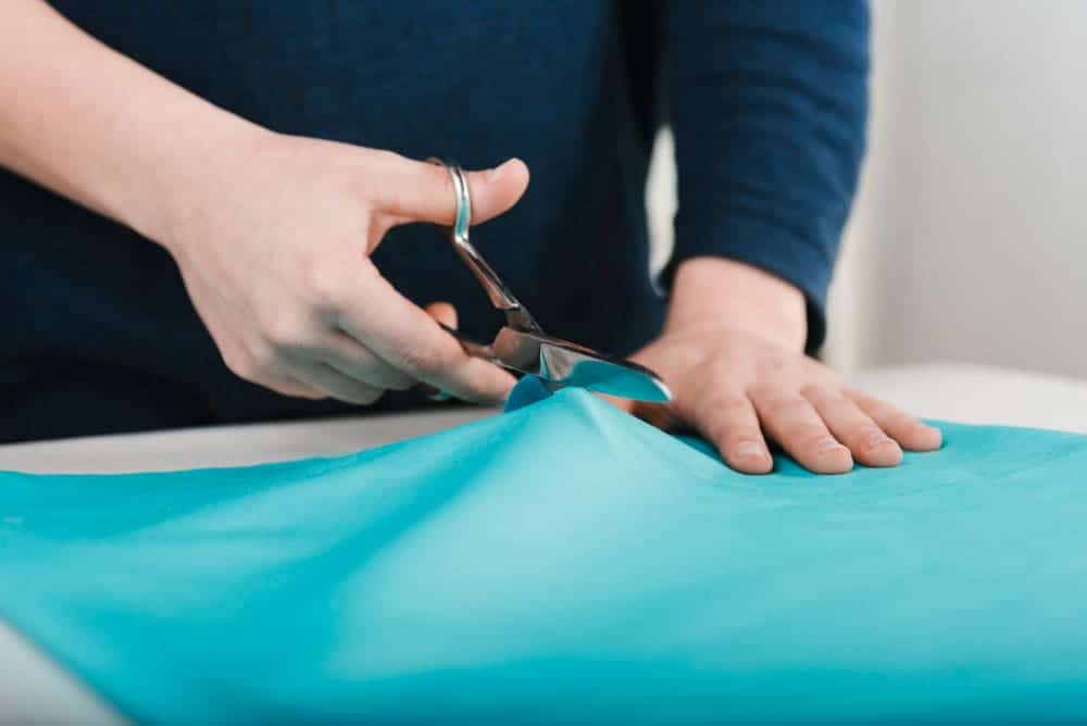 close up man cutting blue fabric