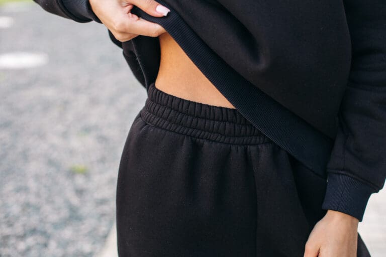 close up young woman wearing black tracksuit lifting hoodie with her hand female fashion copy space