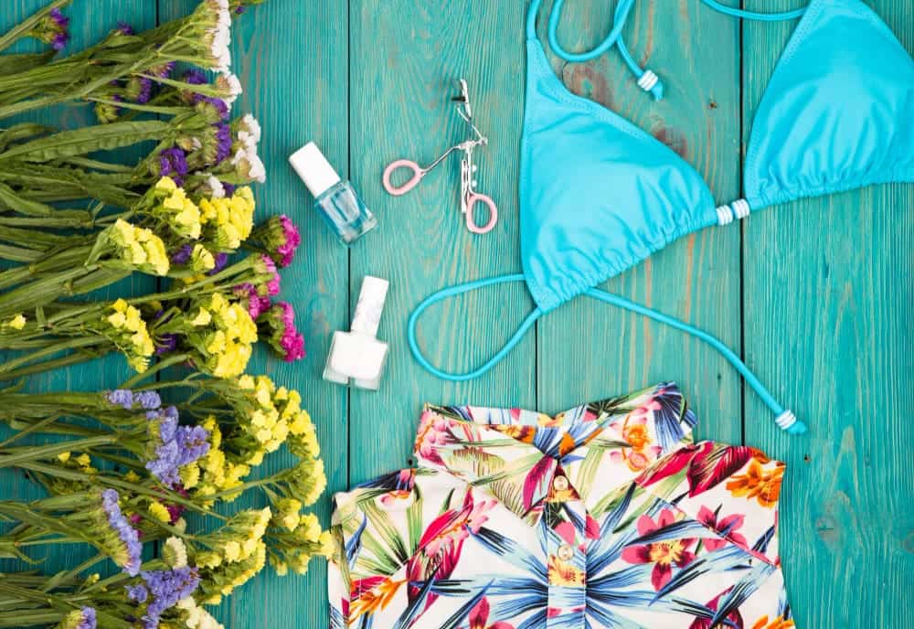 How To Make Swimsuit Bottoms Smaller Without Sewing? 3 summer women s fashion with colorful flowers dress swimsuit cosmetics makeup bijou essentials blue wooden background