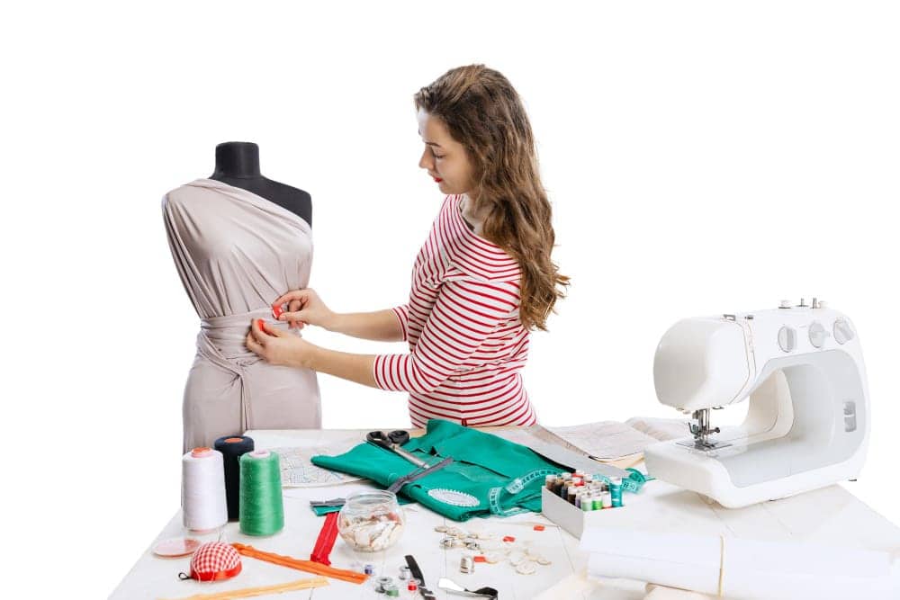 cropped portrait young woman sewing dress isolated white background