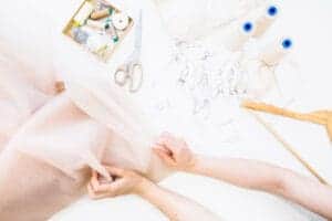 How To Sew Pointe Shoes For Beginners? At Home Guide! elevated view female designer s hand holding fabric workbench