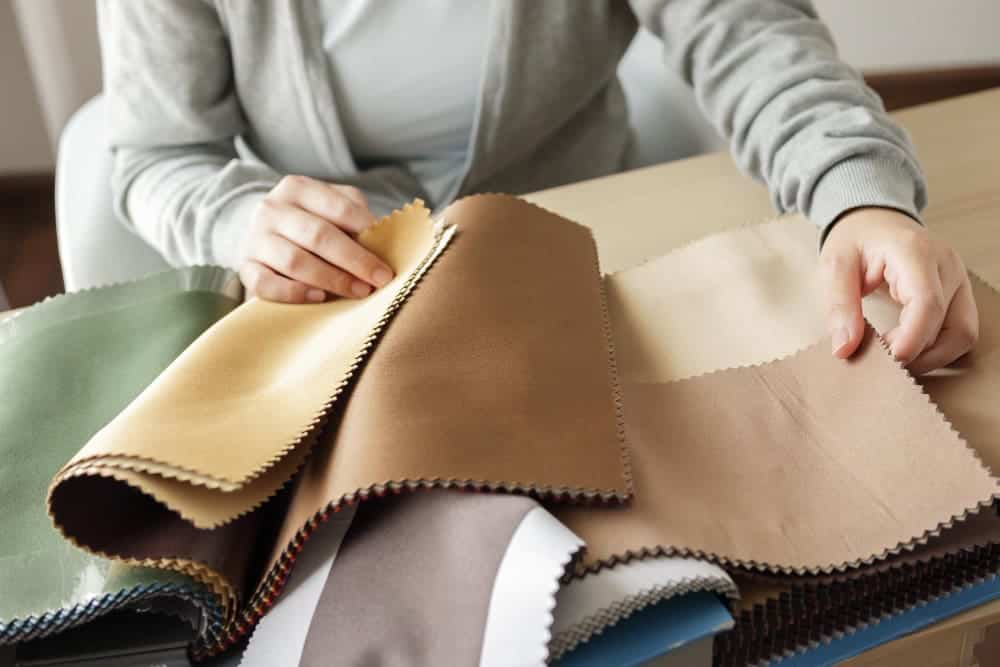female designer with fabric color samples choosing textile curtains