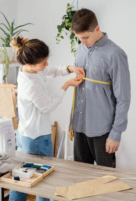 female tailor measuring male clients shirt