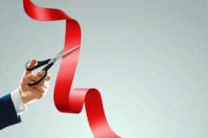 grand opening with red ribbon scissors businessman s hand holds scissors cuts red ribbon light background closeup copy space