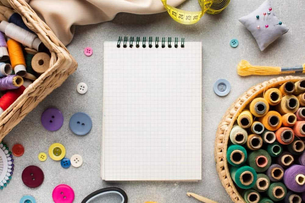 top view notepad surrounded by needlework