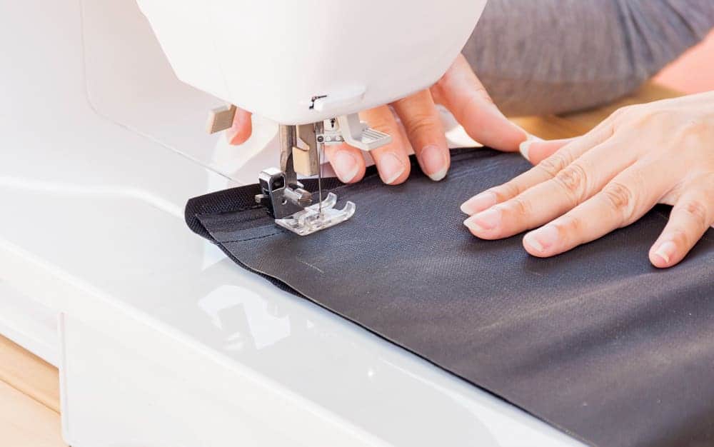 woman s hands doing her patchwork using sewing machine