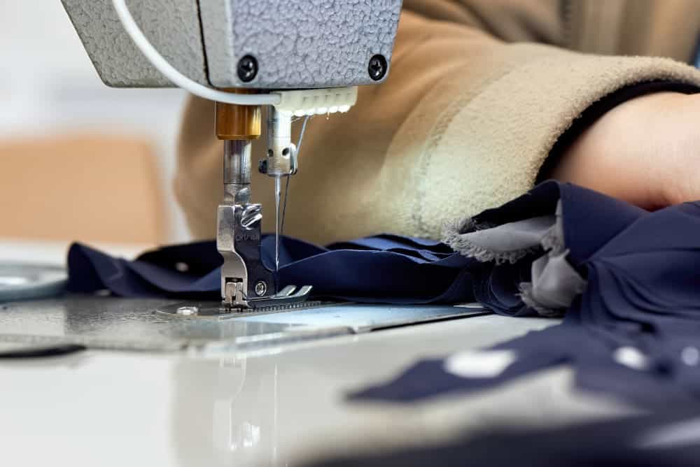 woman working sewing machine with blue fabric